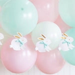 Pastel-colored balloons with bunny banner decorations on a white background