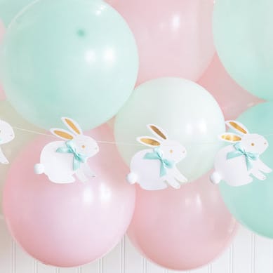 Pastel-colored balloons with bunny banner decorations on a white background